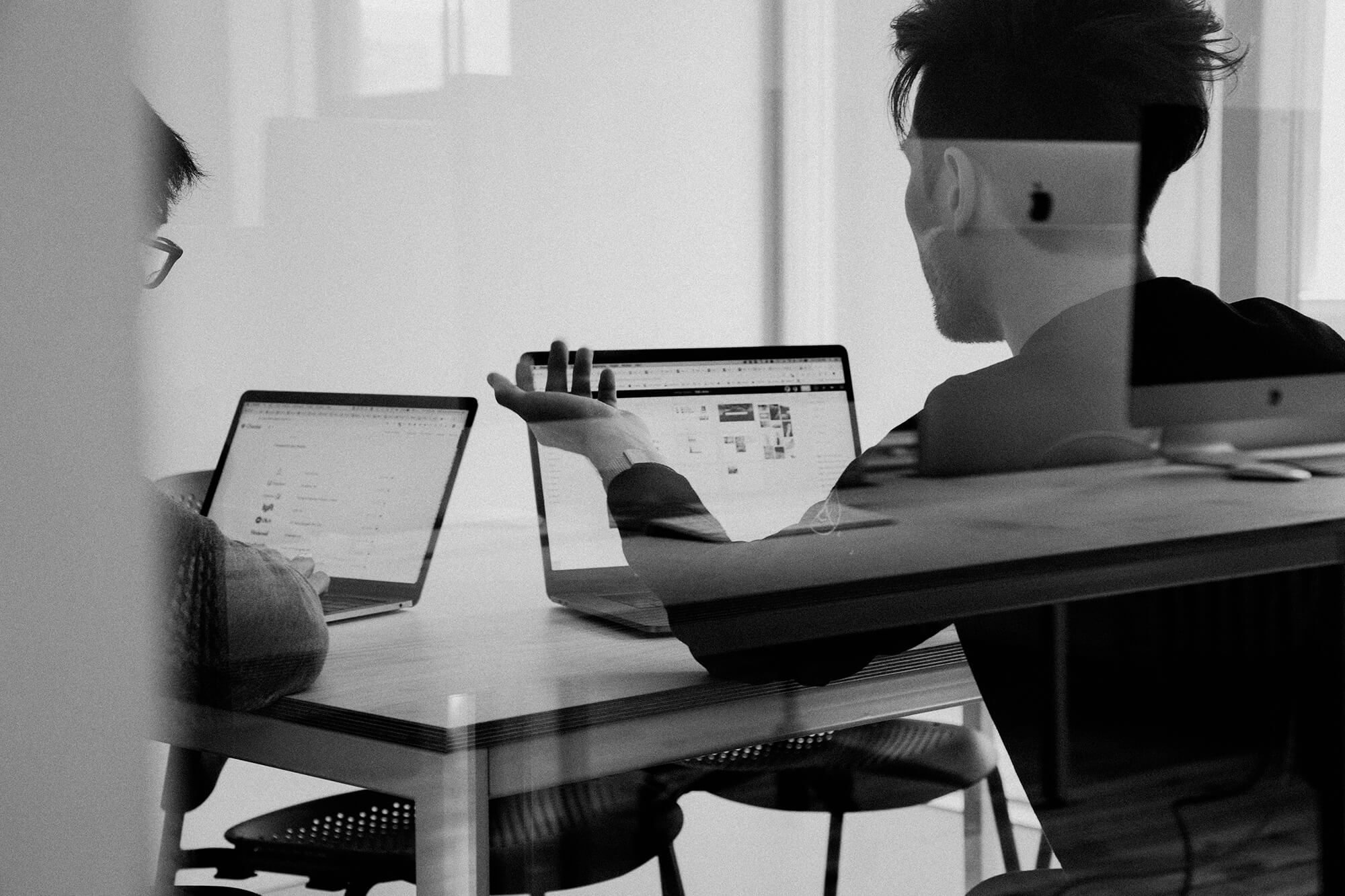 Deux collaborateurs en train de discuter devant leurs ordinateurs